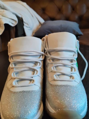 Jordan 11 metallic silver  - .Säljer ett par snygga vita sneakers med glittrig silverdetalj över tåpartiet som ger en riktigt fin och unik look. Perfekta för både vardag och festligare tillfällen när du vill ha bekväma skor som ändå sticker ut lite extra. Färg: Vit med silverglitter Modell: Chunky sneakers Skick: Bra skick, se bilder för detaljer Bekväma och lätta att matcha med olika outfits