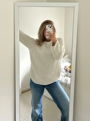 Vit fluffig stickad tröja - Mysig vit stickad tröja med oversized passform och långa ärmar. Tröjan har en fluffig struktur och rund halsringning, perfekt för sena sommarkvällar eller för den kalla vintern. Går att matcha till en massa olika underdelar.