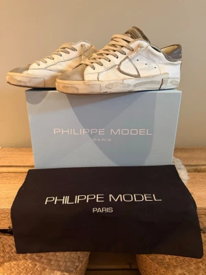 Philippe Model sneakers - Snygga vita sneakers från Philippe Model med grå detaljer och beige mocka på tån. Storlek 42. Använda men i bra skick. Kvitto finns, meddela mig isf.