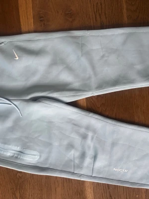 Ljusblå NOCTA x Nike mjukisbyxor - Säljer ett par ljusblå mjukisbyxor från Nike och NOCTA-kollektionen.  Lite mindre i storleken