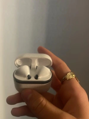 Vita trådlösa in-ear hörlurar - Snygga vita trådlösa in-ear hörlurar med laddningsetui i texturerad plast. Hörlurarna har en stilren design med svarta detaljer i ändarna och passar perfekt för musik, poddar och samtal på språng.