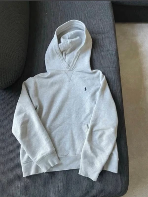  Ralph lauren hoodie - En stilren ljusgrå hoodie med huva och magficka. Tröjan har en liten broderad logga på bröstet och ribbade muddar vid ärmslut och nederkant. Perfekt för en avslappnad look och enkel att matcha med jeans eller joggers. Skriv om du är intresserad!😊 priset är inte hugget i sten!