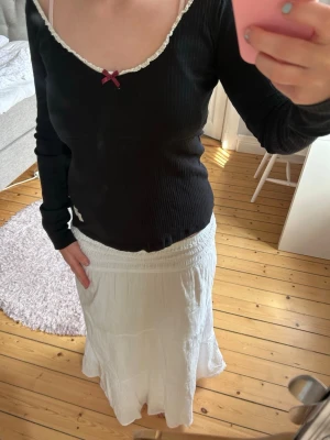 Svart ribbad topp med spetskant - Söt svart ribbad topp från odd Molly med lång ärm, vit spetskant runt ringningen och en liten vinröd rosett framtill. Jättebra skick🩷