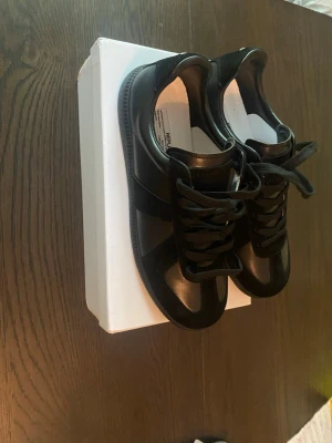 Svarta sneakers i läder och mocka - Snygga svarta sneakers med en mix av slätt läder och mockadetaljer. Klassisk låg modell med svarta skosnören och diskret design. Perfekta för dig som gillar stilrena och tidlösa skor med en modern touch.