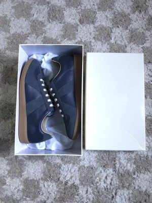 Maison Margiela gats - Ett par väldigt snygga mm gats i färgen pewter/ navy. Skorna är tillverkade med äkta läder vilket gör skorna snyggare med tiden, även att de formas till din fot, perfekt till sommaren om man vill ha något stilren och lowkey. Dessa par är i nyskick. Priset är ej hugget i sten!