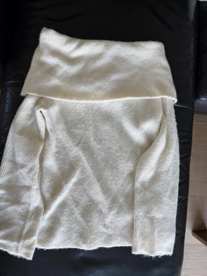 Krämvit stickad off shoulder H&M XS - Mysig krämvit stickad off shoulder från H&M i storlek XS. Tröjan har en bred polokrage och är gjord i ett mjukt, ribbstickat material. Perfekt för lager på lager och en clean look till hösten och vintern.