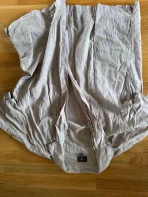 Beige linneskjorta från H&M - Säljer en luftig och stilren beige skjorta från H&M i linnematerial. Skjortan har en avslappnad passform och är perfekt för varma dagar. Klassisk krage och lång ärm, enkel att matcha till olika outfits. XL men passar som L