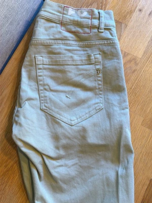 Ljusa Dondup jeans - Snygga ”ljusgröna” jeans från dondup. Storlek 31 modell George.  klassisk femficksmodell och raka ben. Jeansen har diskreta sömmar och en liten logga på bakfickan. Tillverkade i mjukt bomullsmaterial med lite stretch för extra komfort. Perfekta för en clean och stilren look. Köpa i butik. Kvitto finns. Som nya, använda ca 10 gånger. 