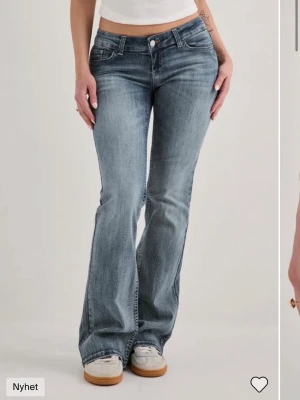 Bootcut jeans med låg midja från Nelly - Säljer ett par snygga bootcut jeans från Nelly med superlåg midja. Jeansen är i en klassisk mellanblå tvätt med lätt slitning.