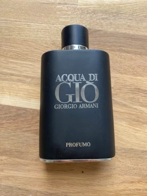 Acqua di Giò Profumo parfym - Acqua di Giò Profumo från Giorgio Armani är en elegant parfym i en matt svart flaska med silverdetaljer. Flaskan har en stilren, rektangulär form och är tillverkad av glas med metallisk finish på kork och botten. Perfekt för dig som gillar exklusiva dofter. Se vilder för egen uppfattning om hur flaskan ser ut, små skafor finns på locket.