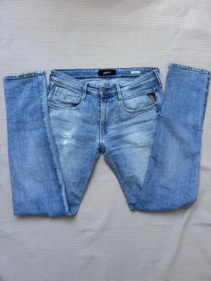 Replay Anbass w32 - Snygga ljusblå jeans från Replay, modell Anbass. Klassisk femficksdesign med Replay-logga på myntfickan och diskreta slitningar framtill. Jeansen har raka ben och är tillverkade i mjuk denim med lätt stretch för skön passform. Storlek w32 l34