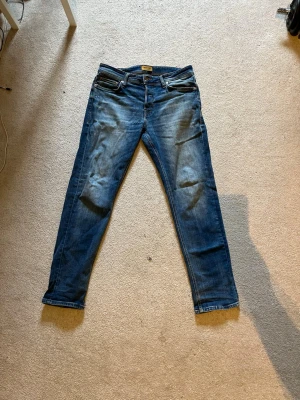 Blå slim fit jeans med slitningar - Snygga blå slim fit jeans med lätt slitna detaljer och klassisk femficksdesign. Jeansen har normal midja och raka ben, perfekta för en avslappnad och trendig look. Materialet är denim i bomull med lite stretch för extra komfort. Nypris 1000kr Storlek W31 L32