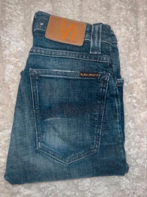 Nudie jeans  - Mörka jeans från Nudie Jeans, modell High Kai med kontrastmönster. Midja 31cm, längd 107cm. JAG SKICKAR EJ FLER BILDER NÄR JAG BÄR JEANSEN! för bättre inblick i passformen rekommenderar jag att googla på modellnamnet. För storleksguide kolla måtten noggrant då jeansen alltid kan vara uppsydda heller krympta och jag ej tar emot returer :) s6,4