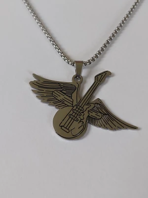 Halsband med gitarr och vingar - Snyggt halsband med ett coolt hängsmycke format som en elgitarr med utbredda vingar. Perfekt för dig som gillar musik och vill ha en unik accessoar med rockig känsla. Kedjan är av klassisk modell och smycket har fina detaljer. Materialet rostfritt stål 