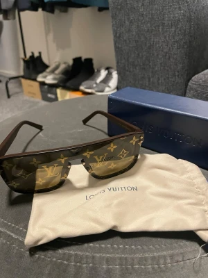 Louis Vuitton Waimea Large square sunglasses  - Snygga solglasögon från Louis Vuitton med rektangulär form och bruna bågar. Glasen har det klassiska LV-monogrammet i guld över hela ytan. Kommer med originalfodral och tygpåse. Perfekt accessoar för dig som vill sticka ut. Nypris ca 5000kr