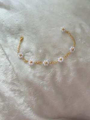 Guldarmband med vita blommor - Sött armband med guldfärgad kedja och små vita blommor 