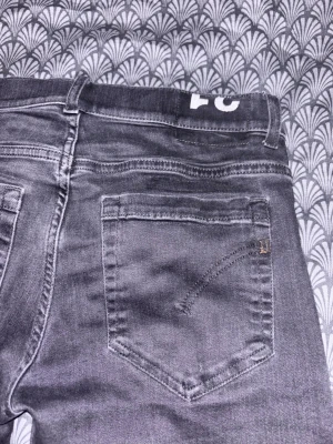 Svarta jeans från Dondup  - Snygga grå jeans med raka ben och klassiska bakfickor. Jeansen har en diskret tvättad look och detaljerad söm på fickorna. Perfekta för en avslappnad stil och passar till det mesta. Feta slitningar har dessa Dondup jeans och är i modellen George.