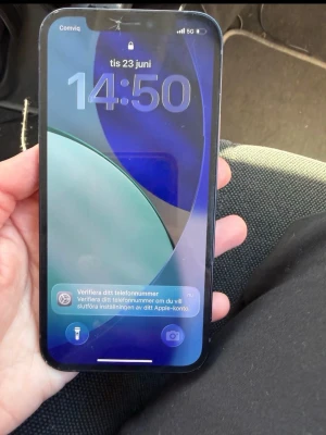 iPhone 12 svart  - Säljer en svart iPhone 12 med 64GB lagring. Telefonen har en stilren design med platt skärm, dubbla kameror på baksidan och Apples klassiska logga. Tillverkad i glas och aluminium, passar perfekt för dig som vill ha en snabb och snygg mobil. Den har sprungit lite framme men det påverkar inte telefonen 