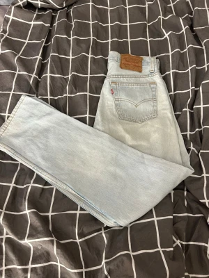 Ljusblå Levi's raka jeans - Säljer ett par klassiska ljusblå jeans från Levi's med rak passform och hög midja. Jeansen har fem fickor, gylf med dragkedja och knapp samt den ikoniska läderlappen bak i midjan. Perfekta för en avslappnad och trendig look. Ända deffekten är lite skada vid där bälte ska sitta
