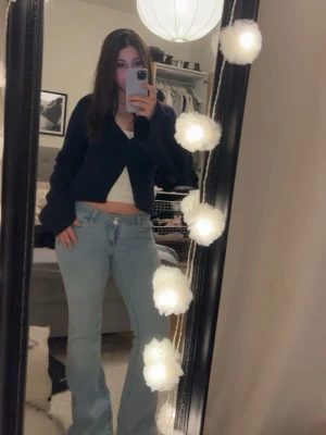 Mörkblå croppad kofta med v-ringning - Trendig mörkblå croppad kofta med v-ringning och långa ärmar. Koftan har en enkel design med knäppning framtill och är perfekt att styla över ett linne eller topp. Passformen är normal och materialet känns mjukt och bekvämt.