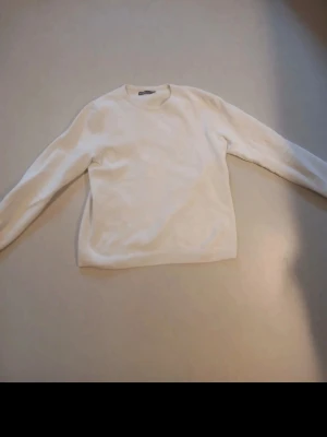 Vit stickad tröja från S.C.W. - Klassisk vit stickad tröja från S.C.W. i storlek XL. Tröjan har rund halsringning, lång ärm och ett diskret rutmönster i materialet. Perfekt att matcha med jeansl för en clean look.