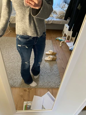 Jättefina lågmidjade bootcut jeans  - Säljer ett par mörkblå bootcut jeans med slitna detaljer och vita kontrastsömmar. Jeansen har låg midja och dekorativa fickor bak med broderade detaljer. Köpta på Gina tricot och helt oanvända! Storlek Xs 14+, skriv gärna vid frågor💗💗
