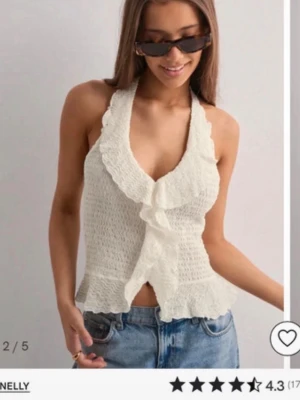 Vit halterneck topp - Supersöt vit halterneck topp från Nelly med volangkant och knyt i nacken. Endast testad! Prislappen är kvar.