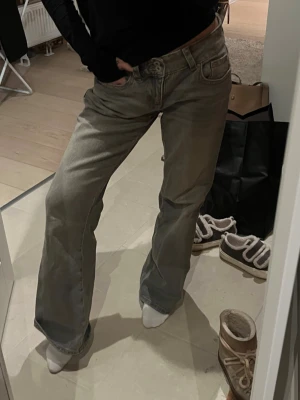 Gråa raka jeans med låg midja - Säljer ett par gråa jeans med bootcut passform och låg midja. Perfekta för dig som gillar en lite baggy stil. Materialet är denim 