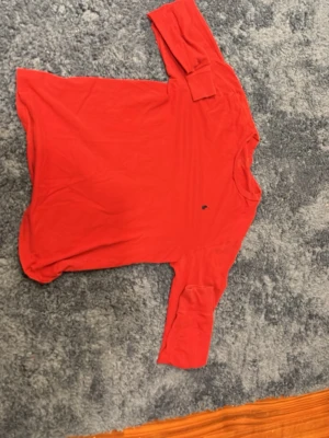 Röd långärmad tröja från Ralph Lauren - Röd långärmad tröja från Ralph Lauren med klassisk passform och liten broderad logga på bröstet. Tillverkad i mjuk bomull, perfekt för en avslappnad och stilren look. Litet hål i armhålan men inget annat. passform är 160/30