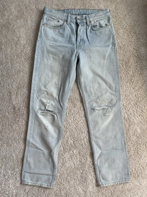 Ljusblå slitna jeans - Ljusblå jeans från bikbok med raka ben och slitningar vid knäna, femficksmodell med läderpatch bak i midjan. Högmidja men går också använda som lågmidjat