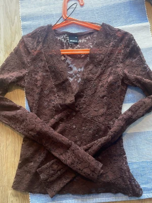 Brun spetsblus med v-ringning - Säljer en brun långärmad blus från Gina Tricot i genombruten spets med blommigt mönster. Toppen har en djup v-ringning och figurnära passform, perfekt för dig som gillar detaljer och romantisk stil. Från Gina den är i bra skick bara att trådarna typ eller något har gått upp som man kanske ser lite💕