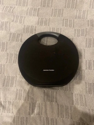 Harman kardon - Snygg och kraftfull bärbar högtalare från Harman/Kardon i svart. Rund design med inbyggt handtag i plast och tygklädd framsida. Perfekt för att ta med sig musiken överallt och ger riktigt bra ljud med stilren look. Strömkabel ingår inte 