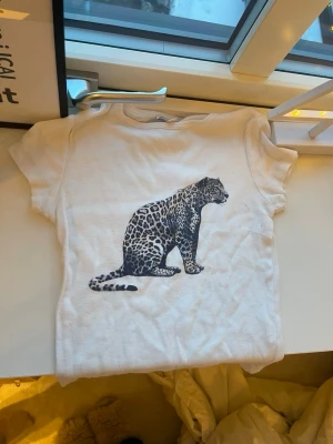 Vit t-shirt med leopardtryck - Vit t-shirt med korta ärmar och ett stort leopardmotiv på framsidan. T-shirten har en klassisk passform och är gjord i mjukt bomullsmaterial. Perfekt för dig som vill ha en cool och enkel look med djurprint. Storlek S men passar XS .från subdued 🤍🤍
