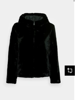 Svart fuskpälsjacka med huva - Mysig svart fuskpälsjacka från Vero Moda med dragkedja och huva. Jackan har en rak passform och är helfodrad för extra värme. Perfekt för kalla vinterdagar och ger en stilren look. Jackan är som ny då jag knapp har haft på mig den.