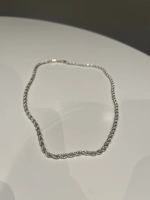 Snyggt tvinnat silverfärgat halsband - Ett stilrent halsband i silverfärg med tvinnad kedja som ger en modern och clean look. Perfekt för dig som gillar minimalistiska accessoarer. Halsbandet har en enkel låsning och passar till många olika stilar. Gansk ny säljer för 500kr