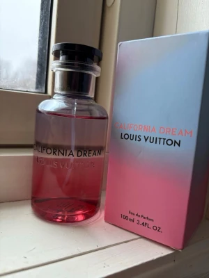 Louis Vuitton California Dream parfym - Louis Vuitton California Dream Eau de Parfum i en snygg glasflaska med rosa till blått färgskiftande design. Flaskan har svart lock med LV-logga och medföljande ask i matchande färger. Volymen är 100 ml och doften är exklusiv och modern.