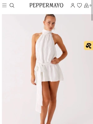 Vit studentklänning PepperMayo - Superfin vit kort klänning från PepperMayo med halterneck, öppen rygg och knytband i midjan. Klänningen har en lätt struktur i tyget och en snygg volangkant nedtill. Perfekt för varma dagar och somriga tillfällen. Passar perfekt som studentklänning