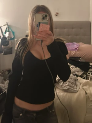 Svart croppad långärmad topp - Aldrig använt, prislapp kvar. Snygg svart croppad topp med lång ärm och djup v-ringning. Perfekt för dig som gillar en enkel men ändå trendig stil. Passar till både jeans och kjol för en cool look.