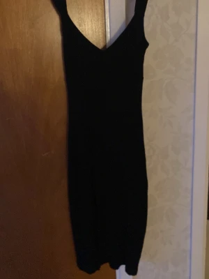 Svart ärmlös klänning - Enkel svart klänning med v-ringning och slits. Klänningen är ärmlös och har en kroppsnära passform. Använd fårtal gånger.