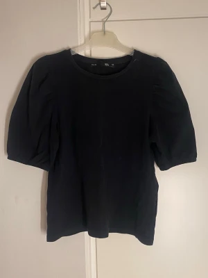Svart topp med puffärm från H&M - En svart topp från lager 157 med puffiga korta ärmar. Använd några få antal gånger. Jätte fin till ett par jeans. 