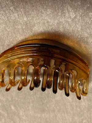 Stor Brun hårklämma  - Snygg hårklämma i klassisk brunmelerad plast med halvtransparent finish. Klämman har en rundad form och stark metallfjäder som håller håret på plats. Perfekt accessoar för att snabbt fixa frisyren och ge en retrovibe till din look. Finns svart färg kvar 