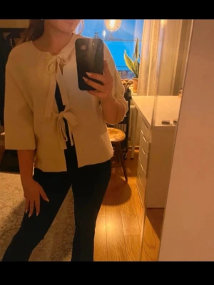 Krämvit kofta med knytband - Säljer en krämvit kofta med trekvartsärmar och två dekorativa knytband framtill. Koftan har en lös och avslappnad passform och är tillverkad i ett mjukt, stickat material. Perfekt för lager på lager och enkel att styla till olika outfits. Tror jag köpte den på Zalando men märket är object. Superfint skick och jätteskön! 