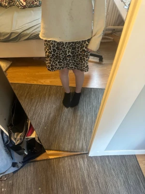 Leopardmönstrad kortkjol - Säljer en snygg kortkjol med leopardmönster i bruna, svarta och beige toner. Kjolen har en avslappnad passform och resår i midjan för extra komfort. Perfekt för dig som vill sticka ut med ett trendigt djurmönster.