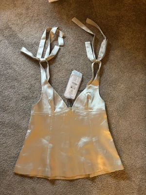 Champagnefärgad satinlinnetopp - Säljer denna superfina fest toppen då den va för liten för mig och jag tappat bort kvittot. Helt ny och helt oanvänd