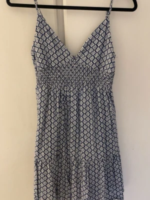 Kort blå/vit mönstrad sommarklänning  - Mönstrad sommarklänning i blått och vitt med v-ringning från mango.  Använt ett fåtal gånger så i mycket bra skick! pris går att diskutera 