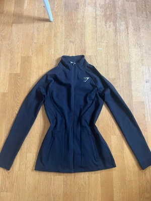 Svart träningsjacka från Gymshark - Snygg svart träningsjacka från Gymshark i storlek XS. Den är figursydd så det sitter jätte snyggt!