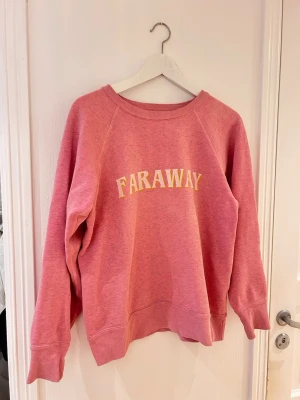 Rosa sweatshirt från Isabel Marant - Rosa sweatshirt från Isabel Marant Étoile med trycket 'FARAWAY' i gult framtill. Tröjan har rund halsringning, ribbade muddar och avslappnad passform. Perfekt för en chill och trendig look.