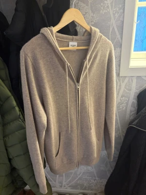 Beige zip hoodie från John Henric - Mysig beige cashmere hoodie från John Henric med dragkedja framtill och två fickor. Perfekt för chill dagar eller när du vill ha en clean och enkel look. 