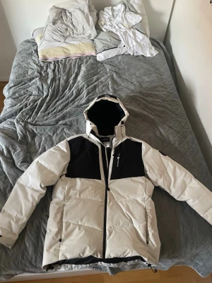 Vit och svart pufferjacka Everest - Skicket på jackan är bra endast dessa fläckar som förstör den, köpte jackan för 3000kr+ från sail racings hemsida. Går säkert att få bort fläckarna vid kemtvätt bara inte min stil längre.