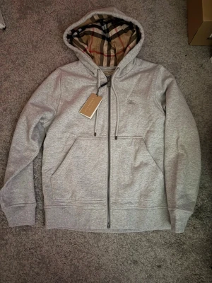 Burberry Hoodie - En klassisk Burberry Hoodie, helt ny säljer då den inte riktigt passa mig, extremt fräsch o fet nu inför sommaren. Storlek S men passar som en M/liten L